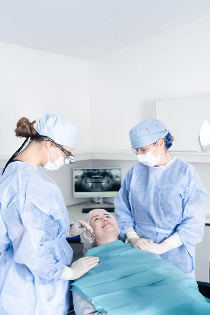 Patient modtager kirurgisk behandling af tandlæger iført sterile dragter hos Tandlægerne Ølandshus
