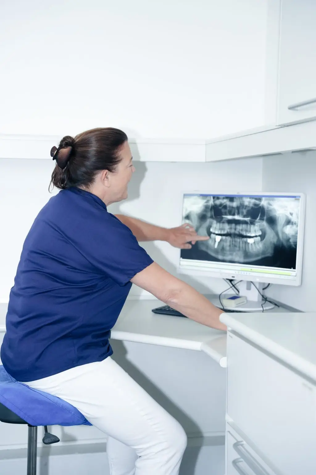 Klinikassistent gennemgår tandrøntgen på skærm i behandlingsrum