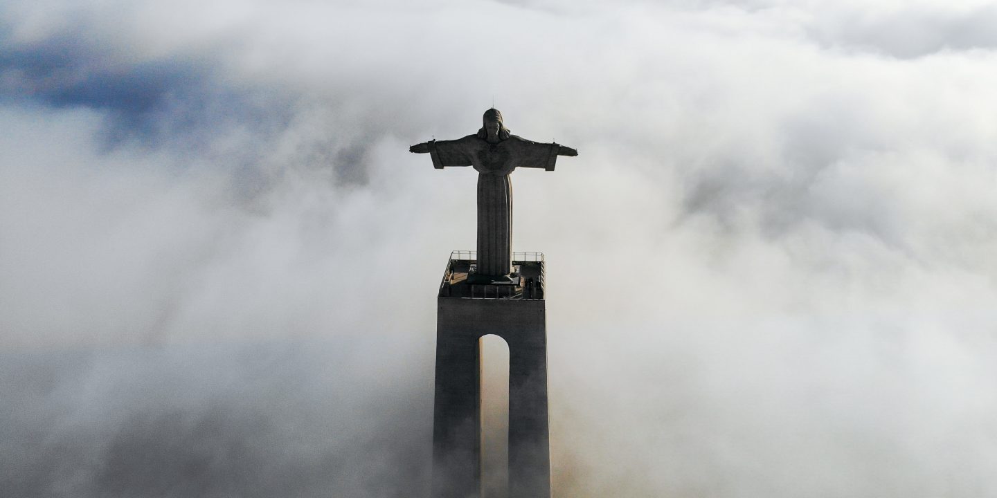 En statue av Jesus med armene ut står høyt over skyene.