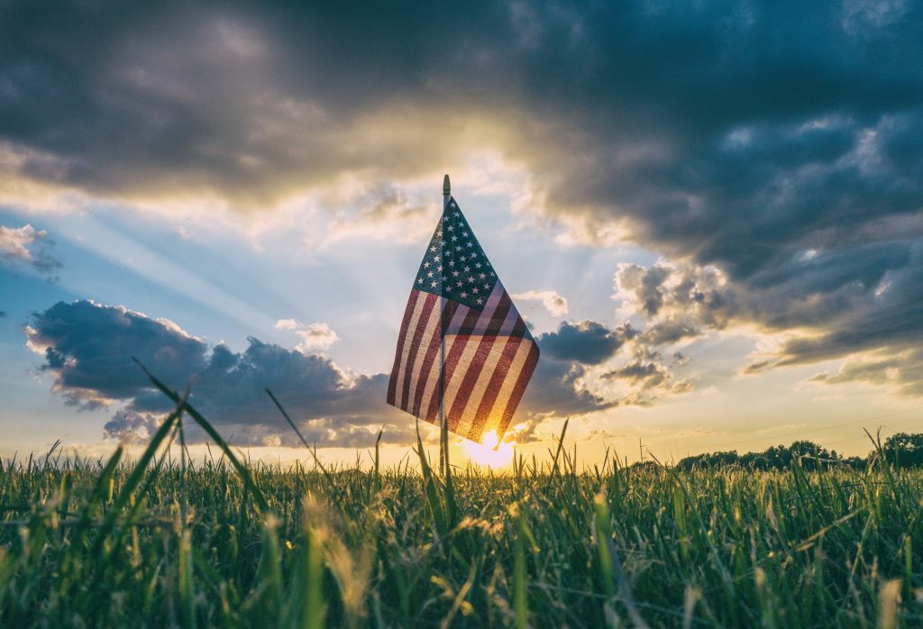 Et amerikansk flagg i solnedgangen, på en gresslette.