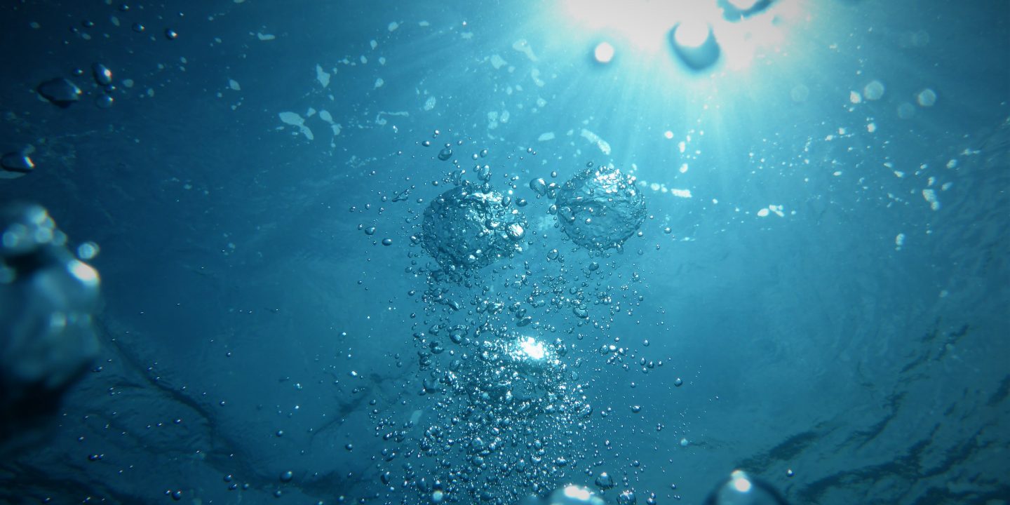 Bilde av vann sett nedenfor med et kraftig lys over. Bobler formeres i vannet.