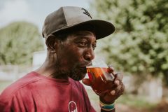 Mann med caps smaker på et glass med øl.