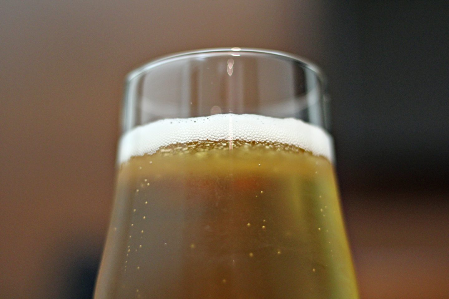 Bilde av et sprudlende glass med øl. Ser bare øverste halvdel av glasset.