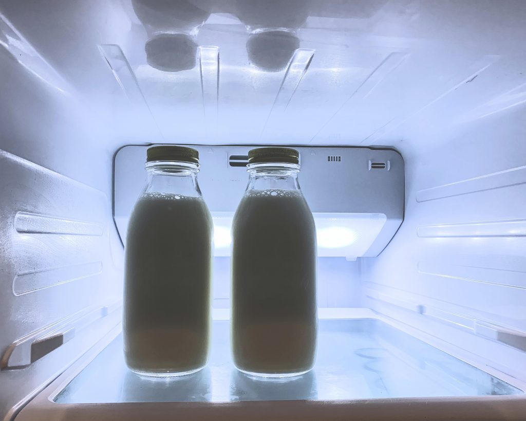 Bilde fra innsiden av et kjøleskap. Vi ser to flasker med melk.