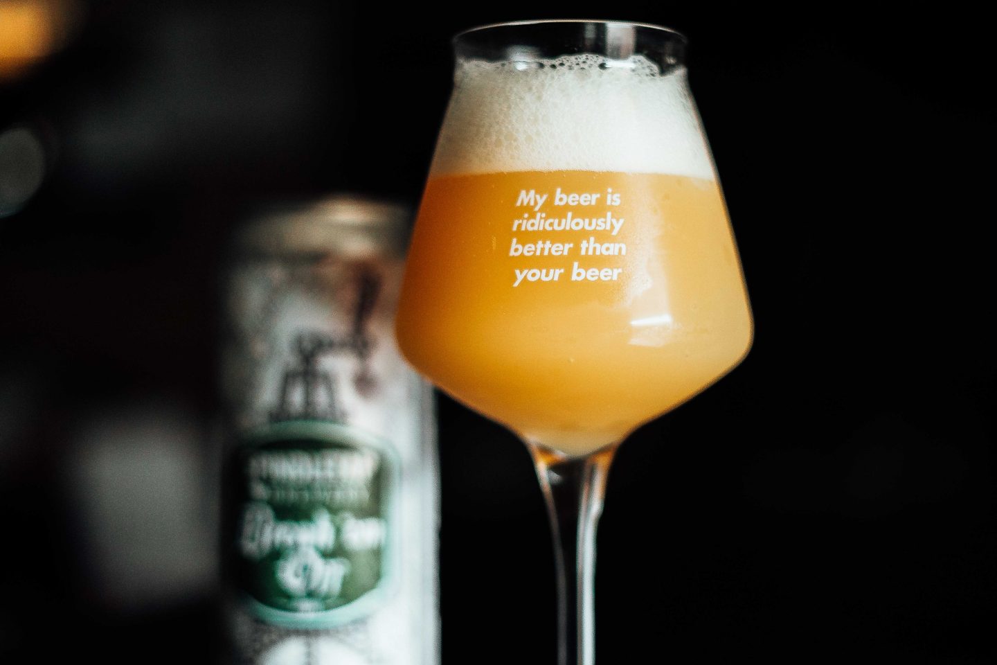 Et teku-ølglass med teksten "My beer is ridiculously better than your beer". Ølet er en tåkete og fyldig NEIPA. Boksen er "blurry" i bakgrunnen.