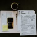 Bilde av en mobil med kalkulator oppe og ark med skatteoppgjør