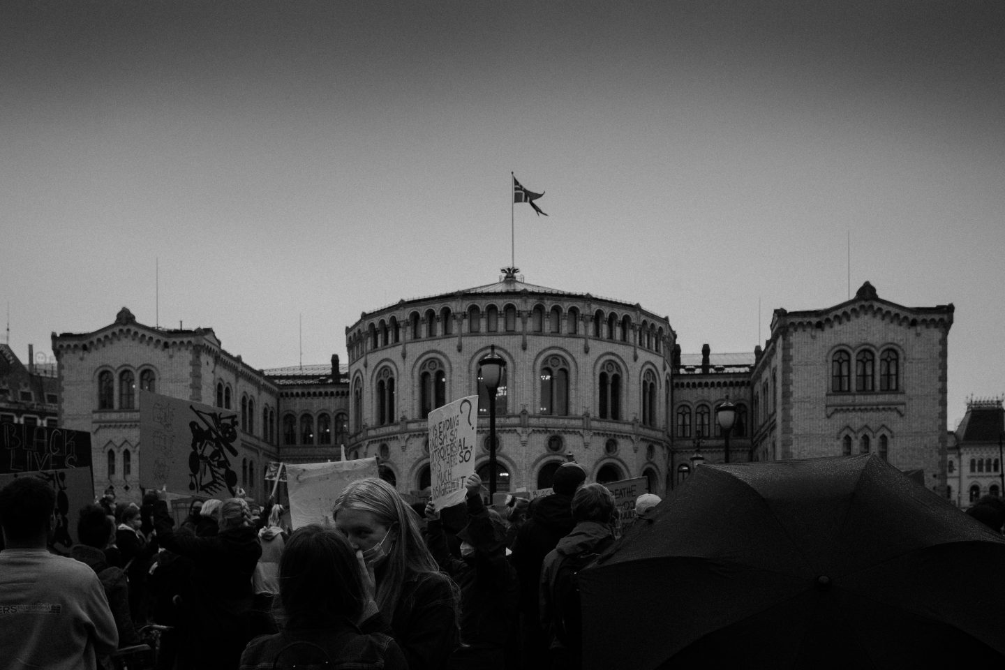 Et bilde av det norske stortinget i Oslo i svart-hvitt med en rekke demonstranter foran.