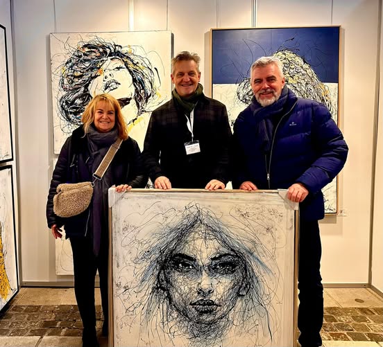 Visitors exploring Ole Hedeager’s art booth, admiring his colorful and expressive drip paintings at The Art Fair – Kunst for Alle.