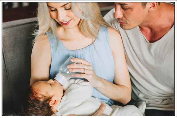 Parents looking at a newborn baby that is feeding from a bottle