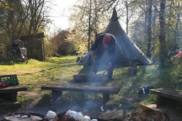 Picture of man with axe in front of a tent