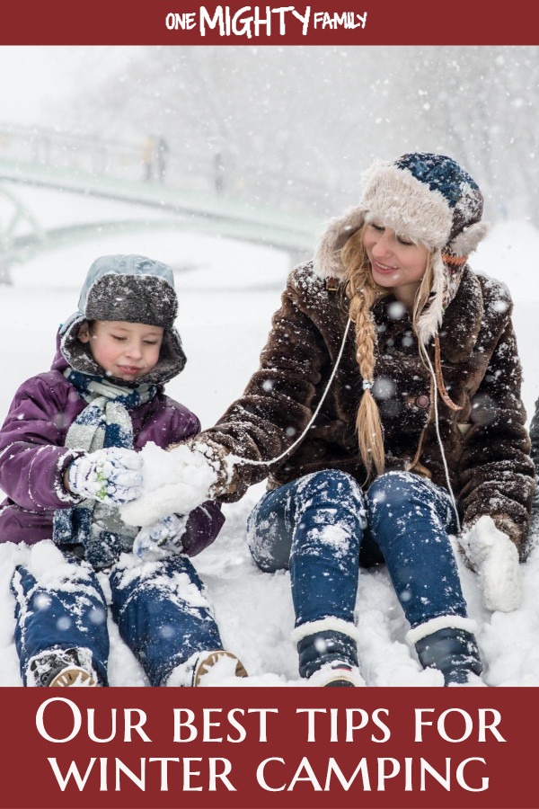 A grown up and a child in winterclothes with snow all around them, happy together outside