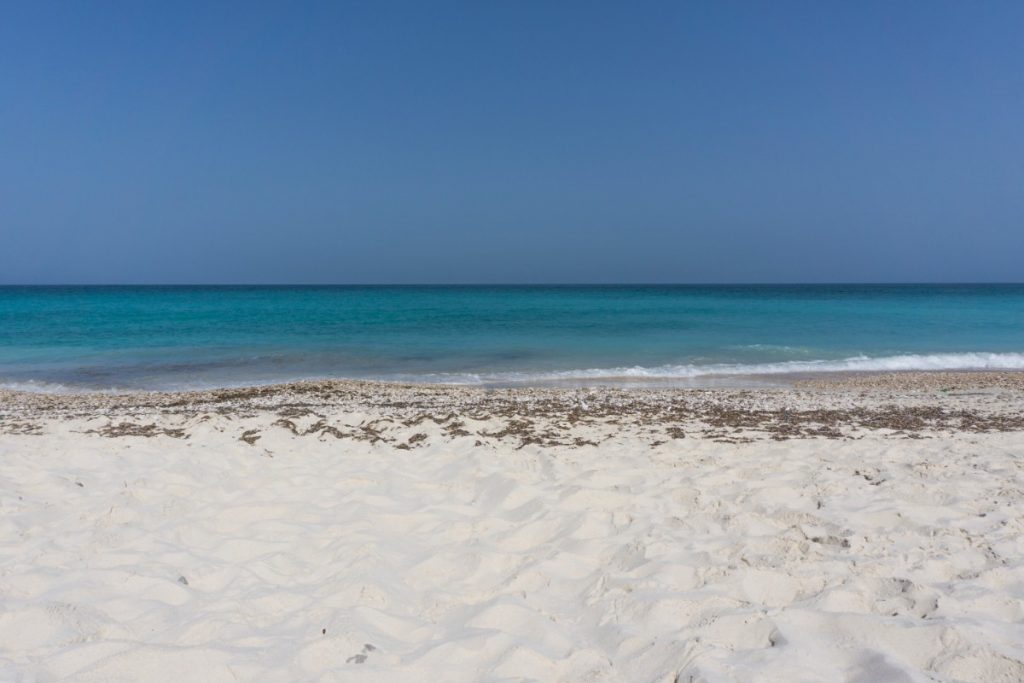 Secret beach in Oman. The picture shows beautiful white sands and turquoise water. 