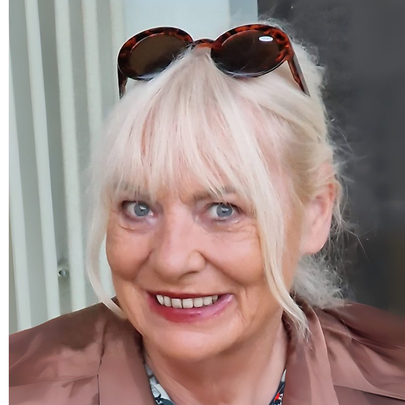Eine Frau mittleren Alters mit hellblonden Haaren und in die Haare gesteckter Sonnenbrille lächelt offen in die Kamera.