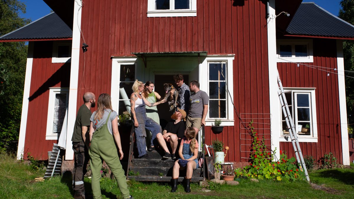 International volunteers at pop-up commune gathering outside traditional Swedish cabin