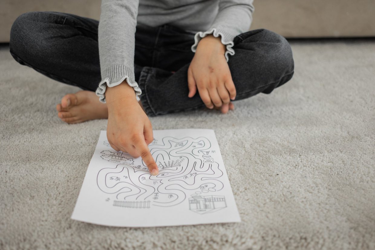 faceless kid sitting on rug and passing painted labyrinth