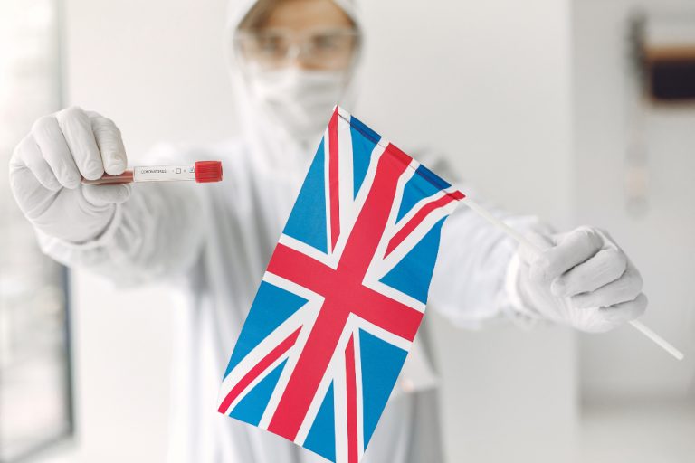 Forskare i skyddsdräkt med ett Coronavirusprov och Storbritanniens flagga