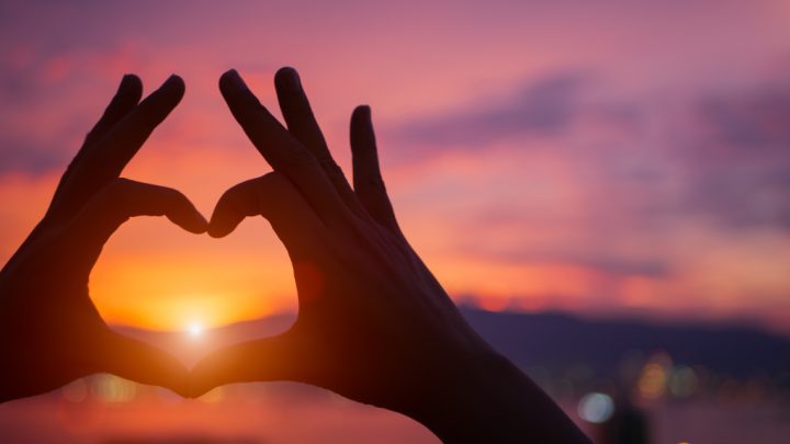 Två händer formar ett hjärta med solen i mitten