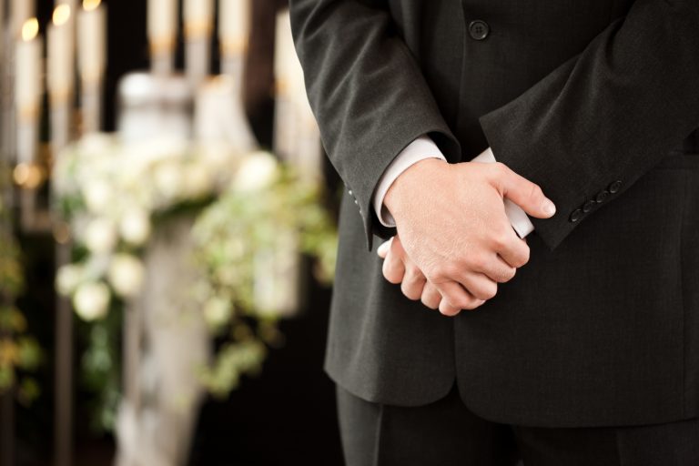Ett par händer och en kostym vid en begravning