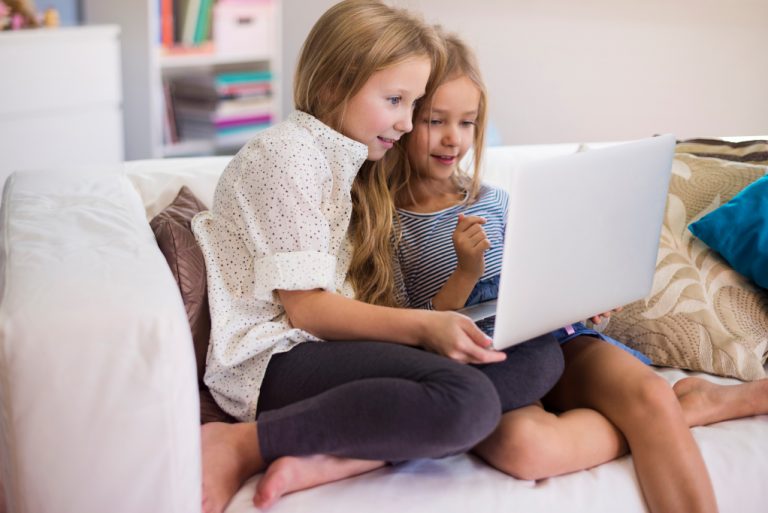 Två flickor sitter framför en laptop