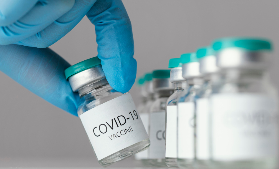 hand i skyddshandske som håller en burk Covid-19 vaccin