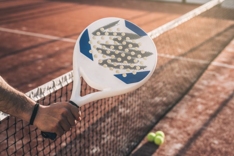 Manlig hand som håller i ett padelracket