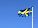 Svensk flagga som vajar mot blå bakgrund