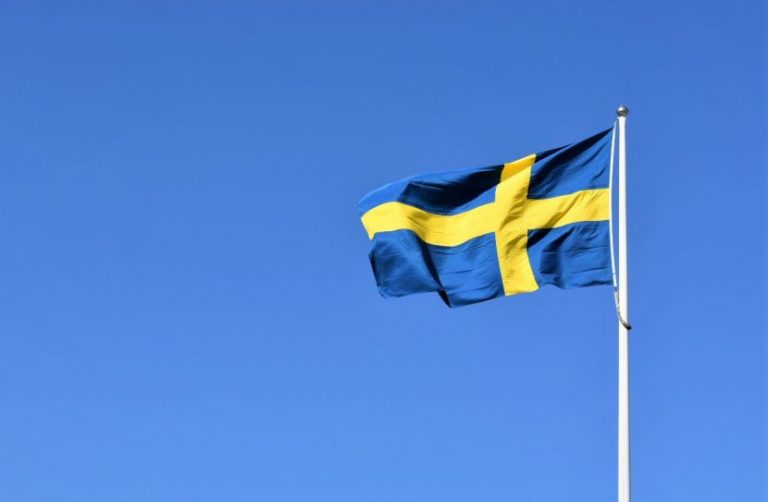 Svensk flagga som vajar mot blå bakgrund