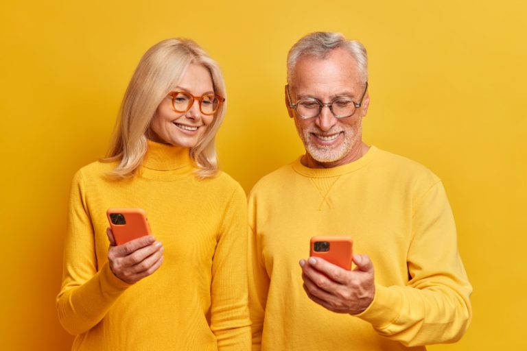 Medelålders par med mobiltelefoner mot gul bakgrund
