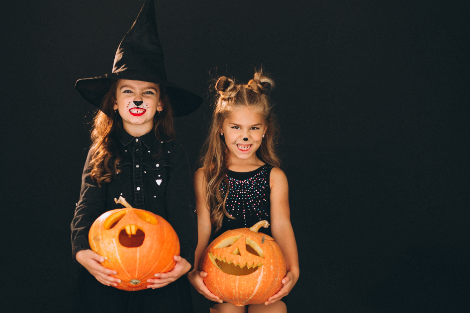 Två flickor utklädda för Halloween som håller i varsin pumpa