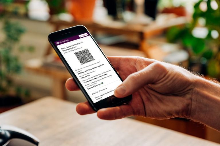 En hand håller en mobiltelefon som visar ett covidbevis