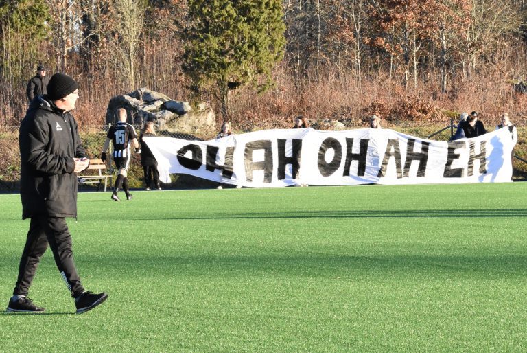 En fotbollstränare promenerar på en fotbollsplan.