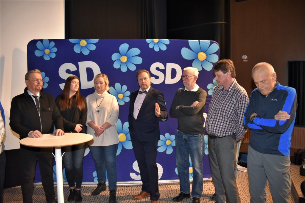 Ett antal sverigedemokrater står och pratar på ett möte