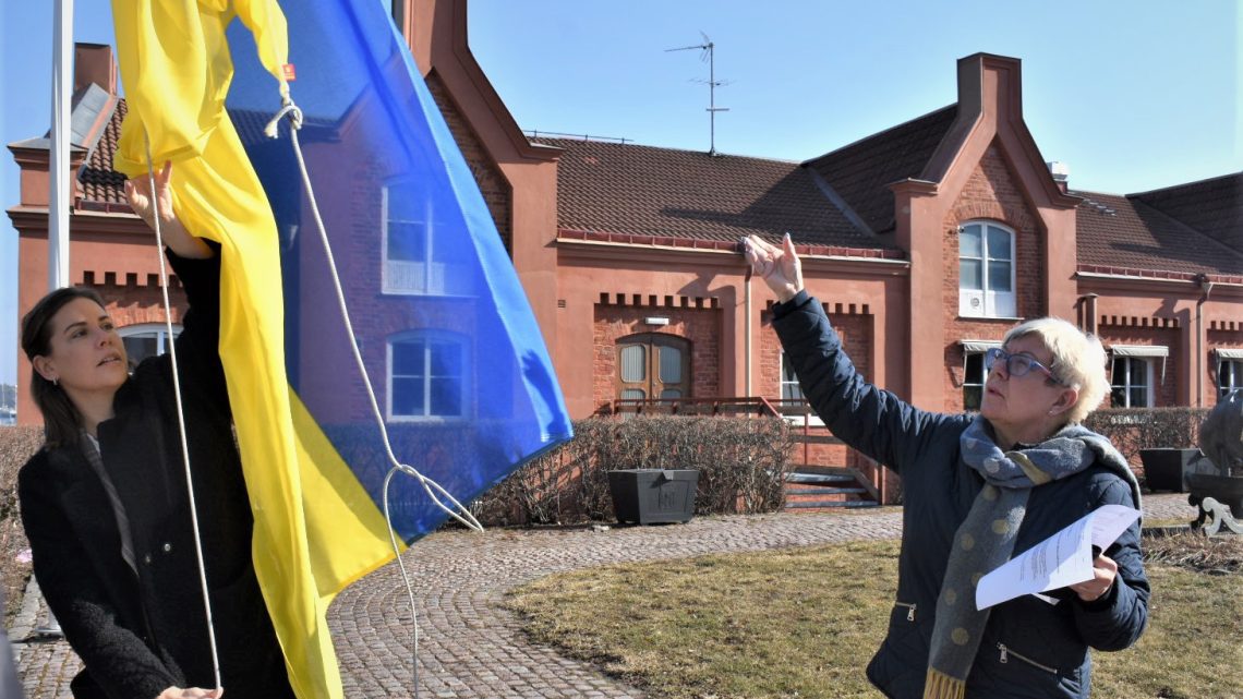 Maria Ihse, kommunikationschef i Oskarshamns kommun, och Yvonne Bergvall (S) hissar den ukrainska flaggan utanför stadshuset i Oskarshamn