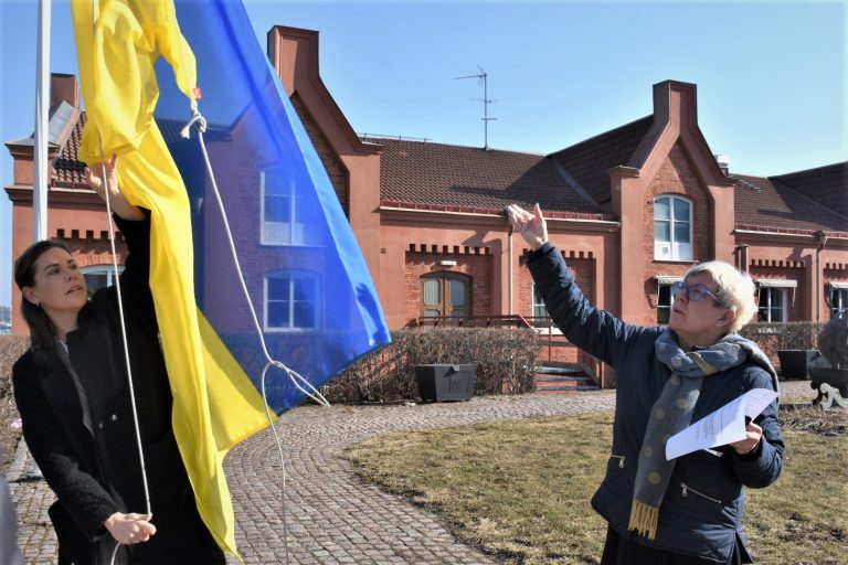 Maria Ihse, kommunikationschef i Oskarshamns kommun, och Yvonne Bergvall (S) hissar den ukrainska flaggan utanför stadshuset i Oskarshamn