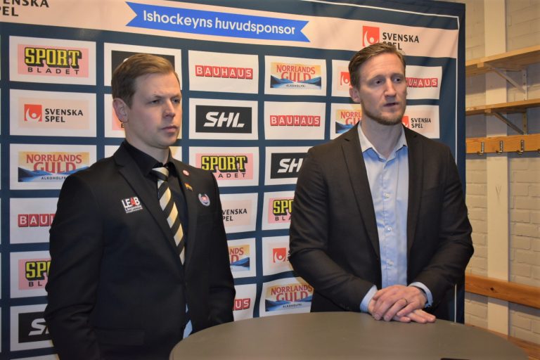 Två hockeytränare står och pratar på en pressträff