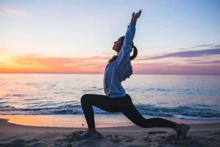 Kvinna gör yoga på stranden