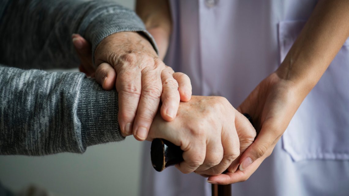 Vårdare håller äldre kvinna i handen