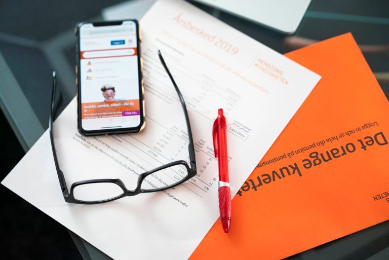 Orange kuvert med årsbesked, mobil och glasögon