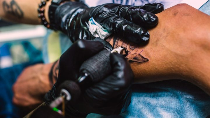Tatuerare arbetar med tatuering på arm
