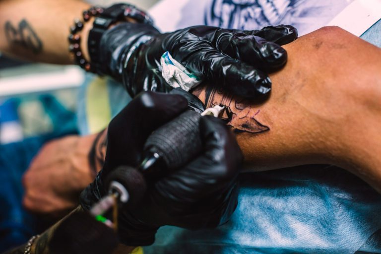 Tatuerare arbetar med tatuering på arm