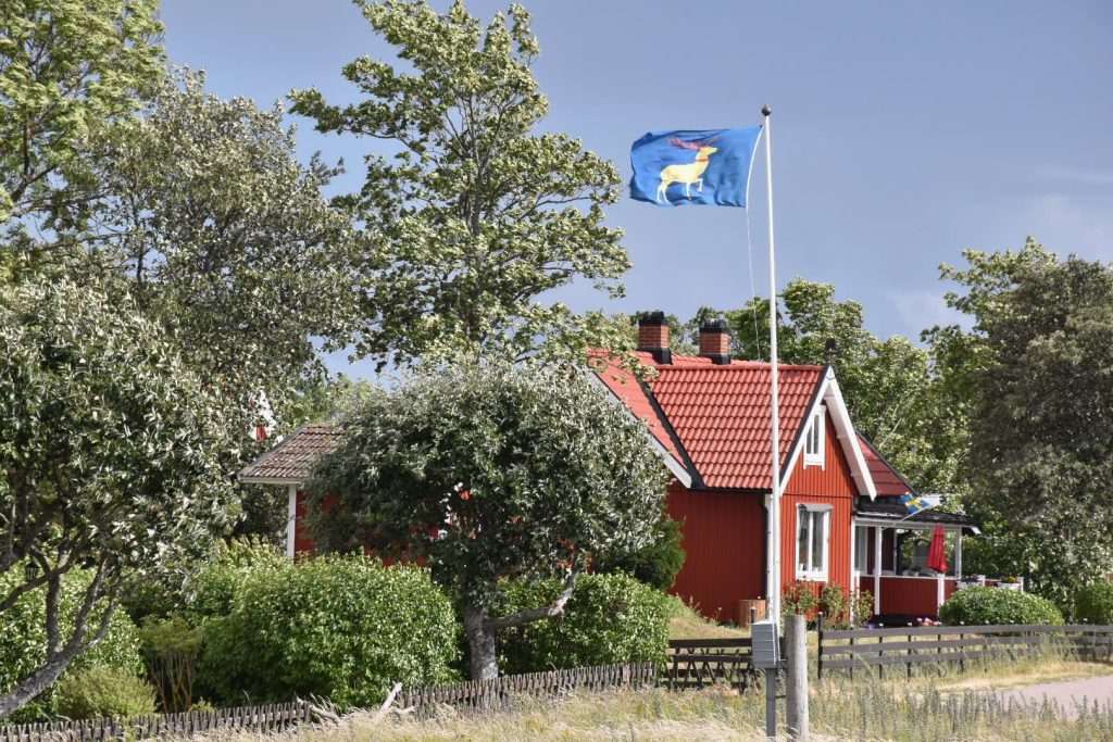 Genrebild Öland, rött hus med vita knutar, öländska flaggan, hus, sommar