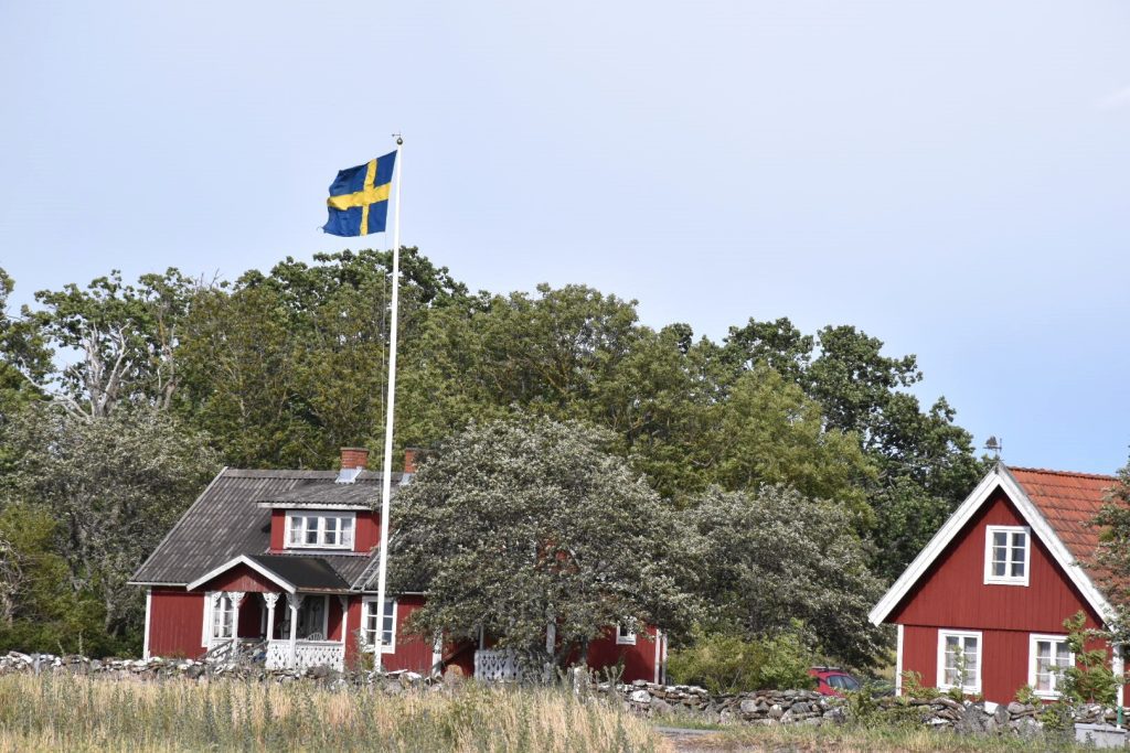 Genrebild Sverige, rött hus med vita knutar, svenska flaggan, hus, sommar