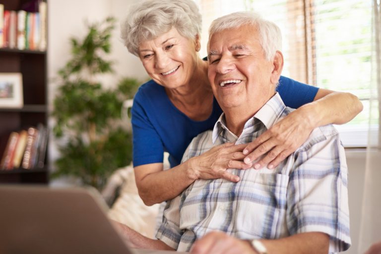 Glada pensionärer som tittar på en dator