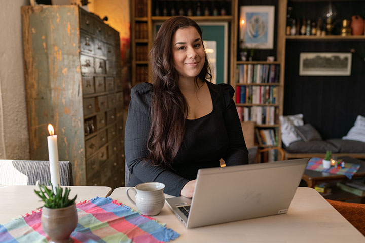 Erika Stadling Holm sitter vid kökbordet med en dator