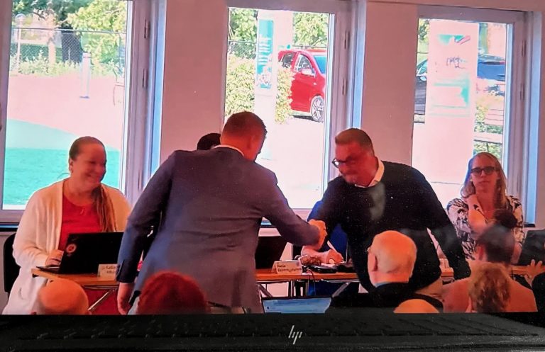 Andreas Erlandsson (S) och Leif Axelsson (SD) tar varandra i hand. Bild från Oskarshamns kommuns webbsända fullmäktigesammanträde