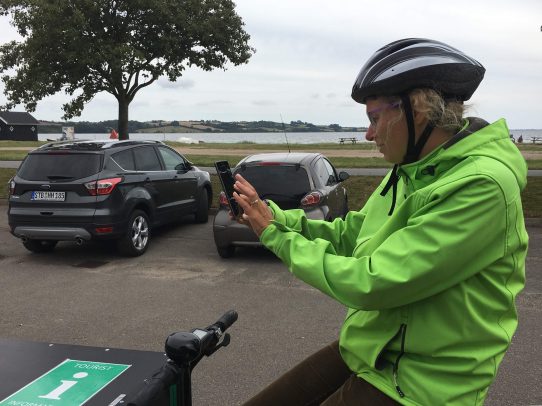 Frau auf Lastenrad bedient ein Handy