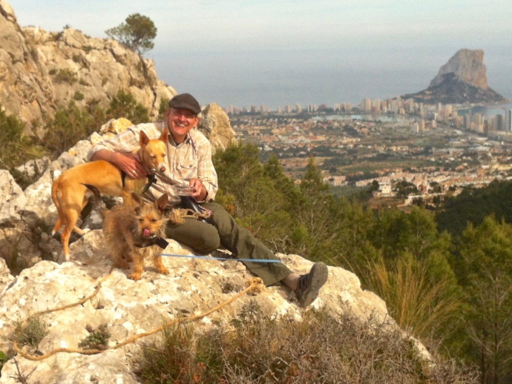 Mann mit zwei Hunden auf Bergspitze