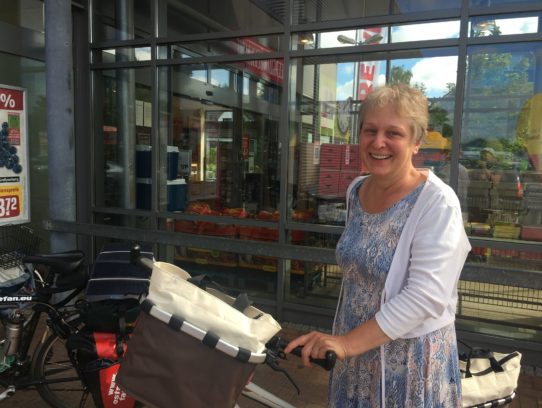 Frau mit Rad vor Supermarkteingang