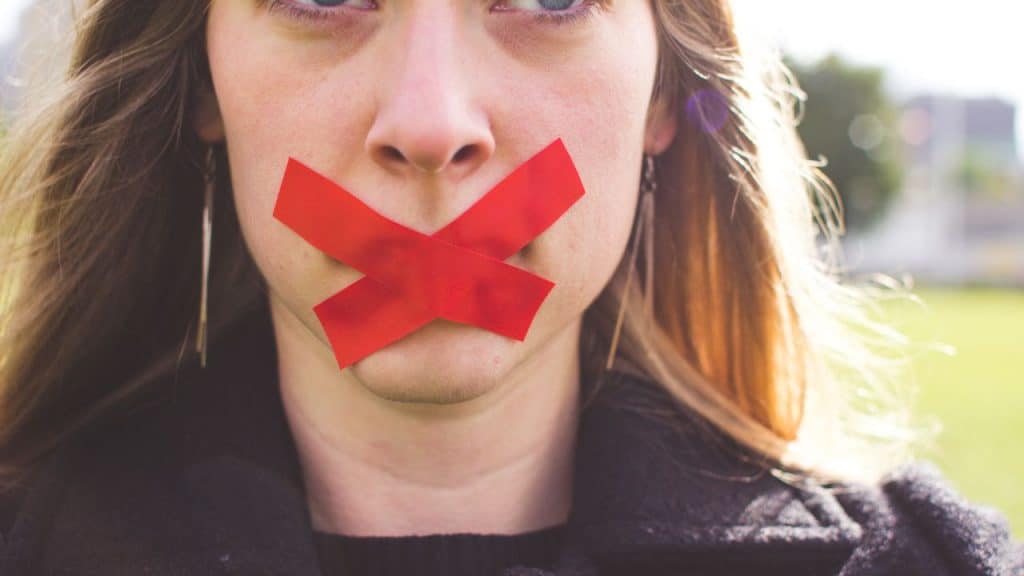 Woman being silent due to trauma and fear which blocks her ability to use her voice