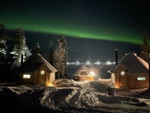 Three huts outside northern lights in poikkijärvi